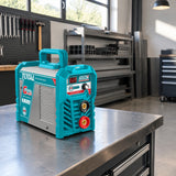 Total TW218028 inverter MMA welding machine resting on a steel workbench in an organized fabrication workshop