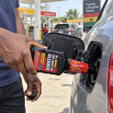 Ghanaian driver pouring Abro IC-509 fuel injector cleaner into a car fuel filler at a petrol station