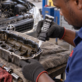 Technician applying a bead of Abro Black RTV Silicone Gasket Maker to an automotive valve cover flange.