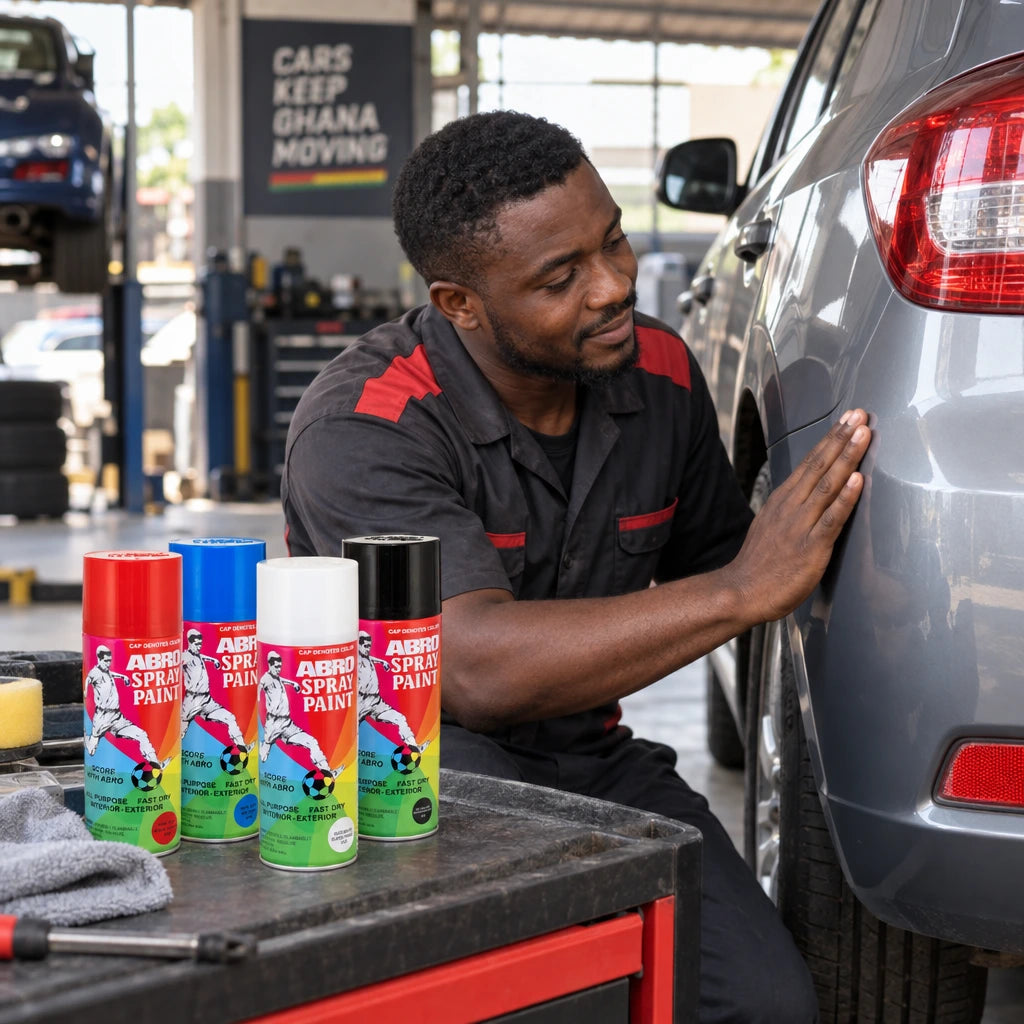 Refinished vehicle trim inspected beside Abro spray paint cans in a Ghanaian auto detailing bay