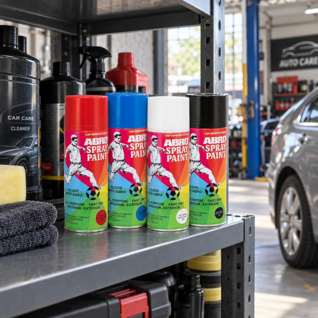 Abro red, blue, white and black spray paint cans stored upright on a shelf in an automotive workshop
