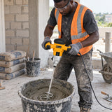 Ghanaian mason using a Coofix dual-handle electric mixer to blend mortar in a construction bucket