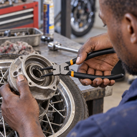Ghanaian motorcycle technician using Coofix bent-head circlip pliers to remove a recessed retaining circlip