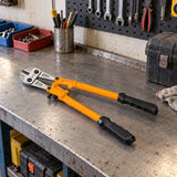 Coofix orange-handled bolt cutter resting on a metal workshop bench beside hand tools