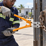 Ghanaian maintenance worker using a Coofix bolt cutter to cut a chain at a metal gate