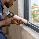 Ghanaian tradesperson using the Coofix 9-inch caulking gun to apply sealant along a window frame