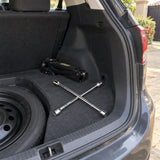 Coofix four-way cross rim wrench resting in a vehicle boot beside the spare wheel