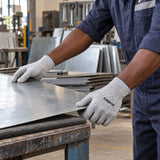 Worker wearing Coofix XL cut-resistant gloves while positioning a sheet-metal panel on a workshop bench