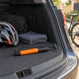 Coofix compact black and orange hand inflator resting in a vehicle boot beside a bicycle