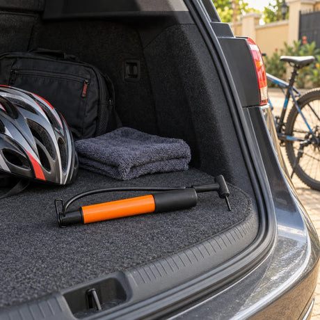 Coofix compact black and orange hand inflator resting in a vehicle boot beside a bicycle