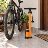 Coofix manual hand inflator standing beside a parked bicycle on a Ghanaian home veranda