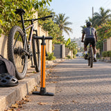 Cyclist riding away after using a Coofix hand inflator, with the pump resting beside the roadside