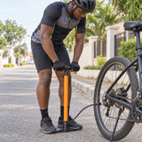 Ghanaian cyclist using a Coofix manual hand inflator to pump a bicycle tyre by the roadside