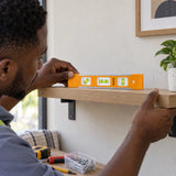 Ghanaian decorator using a Coofix mini spirit level to check a wall shelf during installation