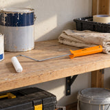Coofix 4-inch paint roller resting on a workshop shelf beside painting supplies