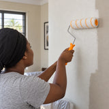 Ghanaian homeowner using a Coofix fibre paint roller to apply paint to an interior wall