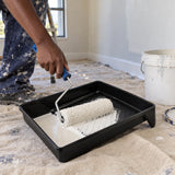 Ghanaian decorator loading a paint roller in a Coofix black plastic paint tray