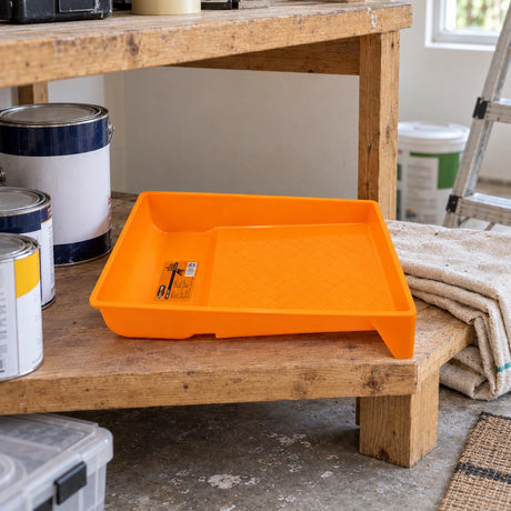Coofix orange paint tray resting on a lower shelf of a home decorating workbench before painting