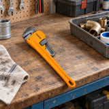 Coofix orange pipe wrench resting on a plumbing workshop bench before use