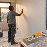 Ghanaian renovator admiring a smooth finished plaster wall with a Coofix trowel in the foreground