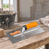 Coofix stainless-steel plastering trowel resting on a mason’s workbench at a wall renovation site