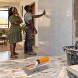 Completed tiled wall inspected in a Ghanaian home with a Coofix toothed plastering trowel resting in the foreground
