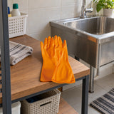 Coofix orange PVC work gloves resting on a utility shelf beside a household sink