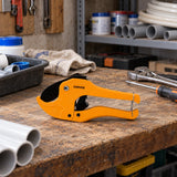 Coofix orange PVC pipe cutter resting on a plumbing workshop bench before use