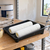 Coofix 9-inch acrylic roller covers resting in a paint tray on a home renovation shelf