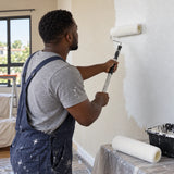 Ghanaian decorator using a Coofix 9-inch acrylic roller cover to paint an interior wall