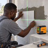 Ghanaian tiler using a Coofix green cross-line laser level to align a wall tile