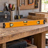 Coofix orange magnetic spirit level resting on a timber shelf in a Ghanaian construction workshop