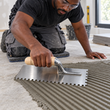 Tiler using the Coofix notched trowel to comb tile adhesive