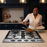 Wider evening kitchen scene with a cook serving a finished meal beside the hob