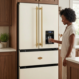 Woman filling a glass from the black water dispenser on the ivory Kaiser Empire refrigerator