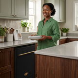 Woman holding clean plates beside the black Kaiser dishwasher
